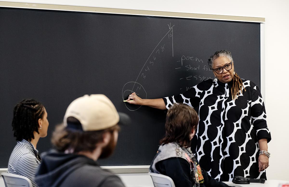 Professor standing and looking at a class while they solve a math equation on a chalkboard