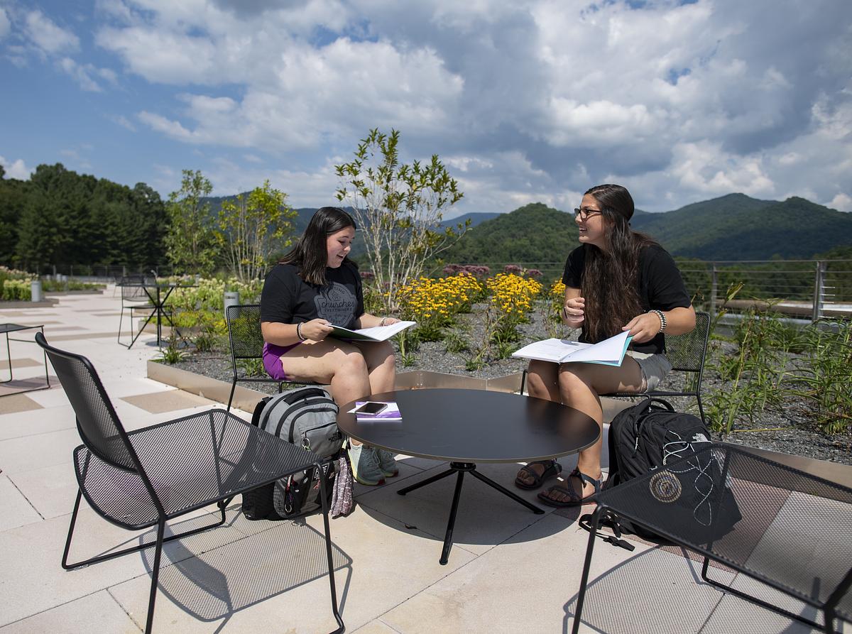 Two students sit outside on Apodaca Terrace studying