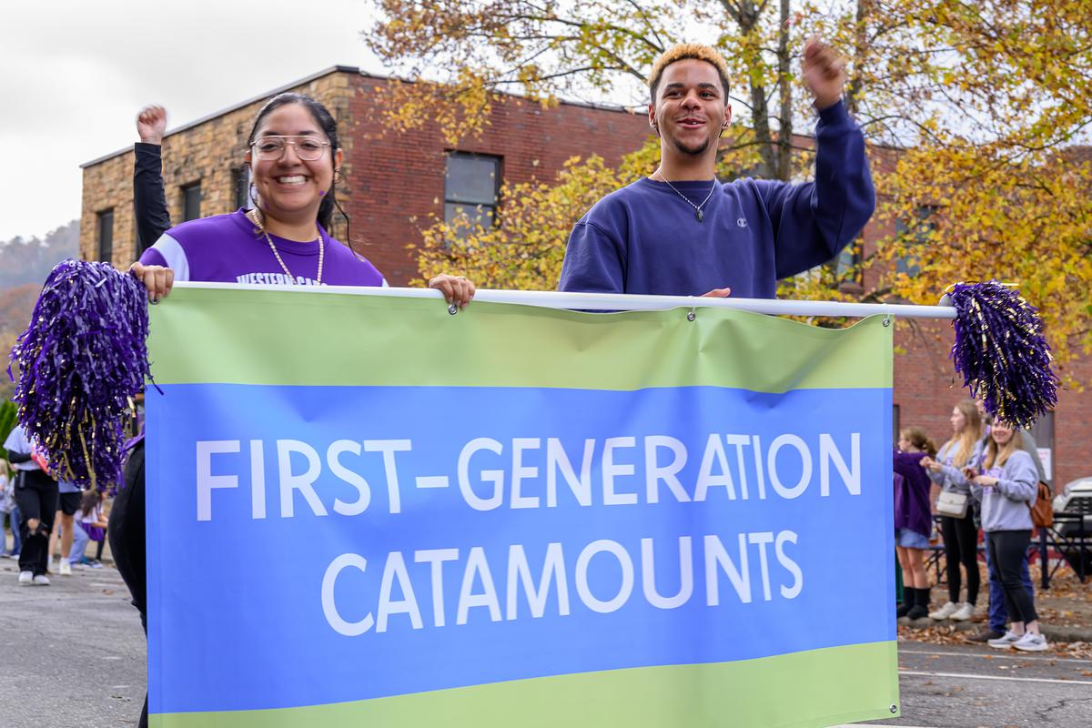 Two students holding FIRST GENERATION CATAMOUNTS banner at Homecoming Parade