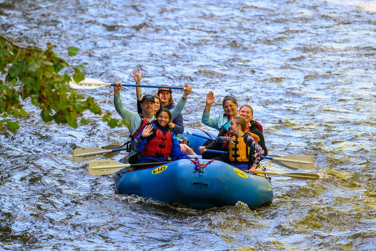 Students and guide at a peaceful section of the Nantahala River raise their paddles up for a photo