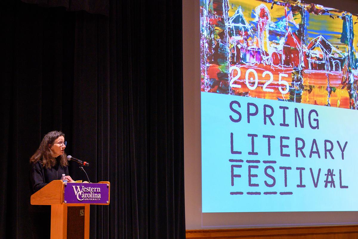 Writer presenting their work at a podium in front of an audience at the 2025 Literary Festival
