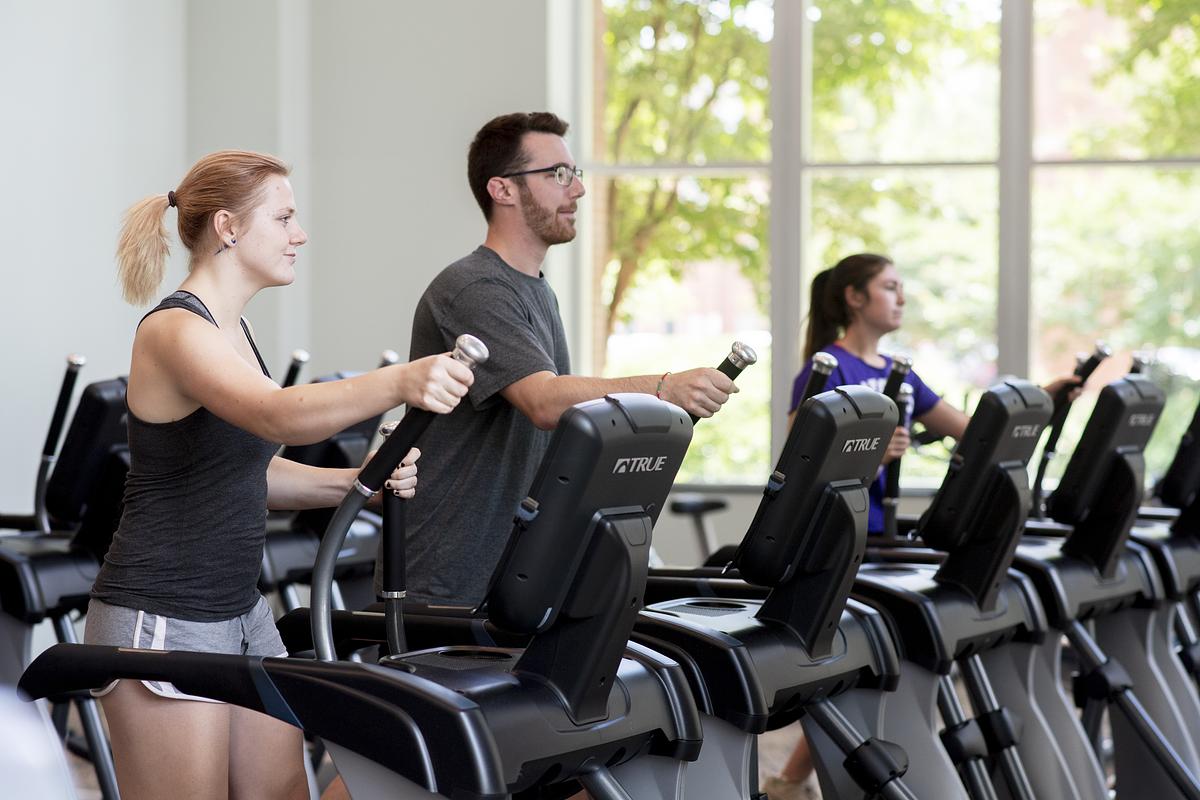 Three students working out on elliptical machines
