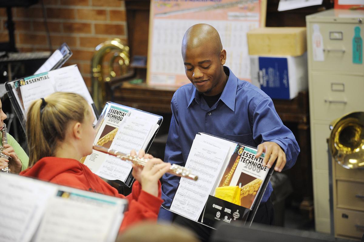 Middle grade student being shown how to perform and read music by their teacher