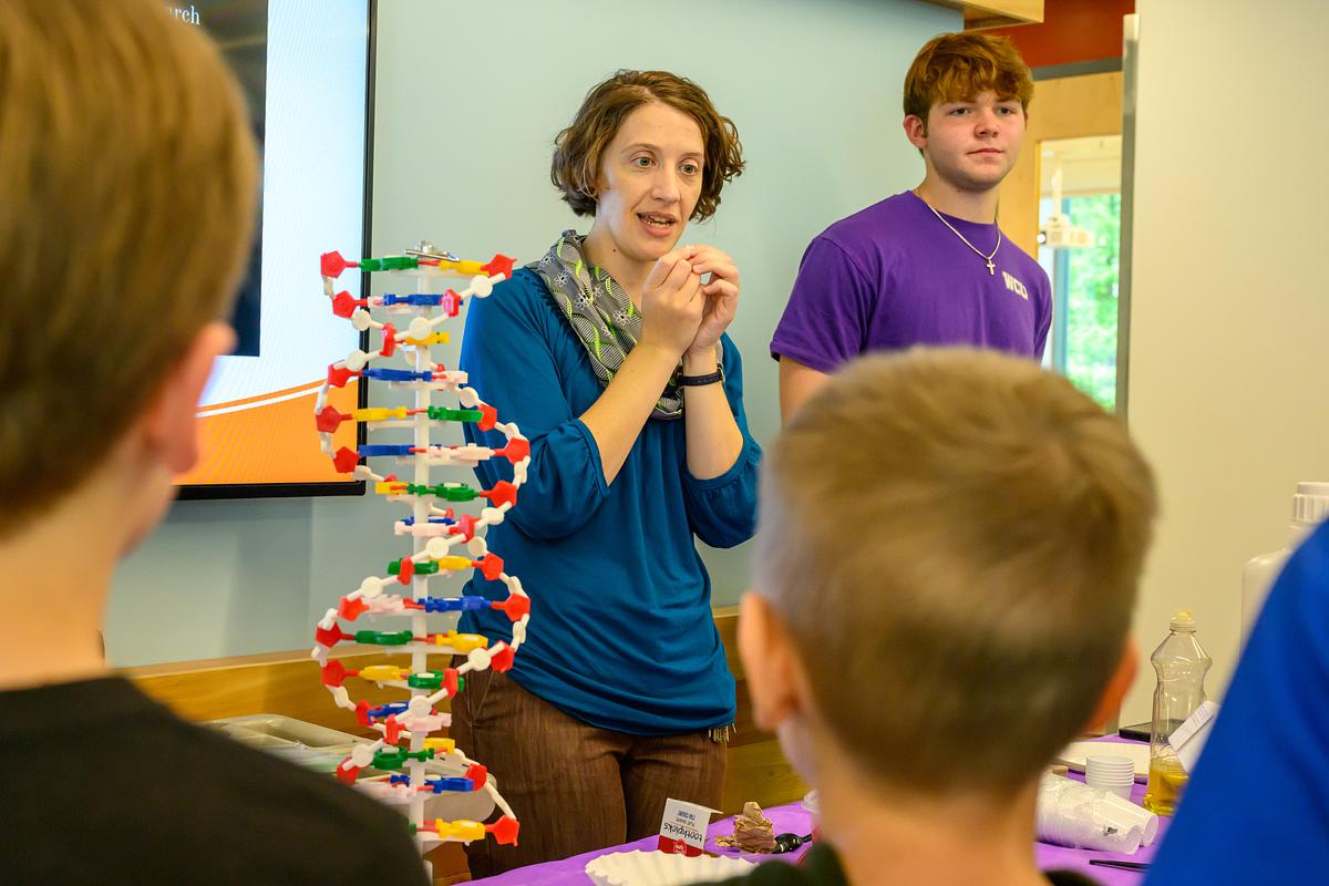 Two individuals teaching K12 students with a DNA model