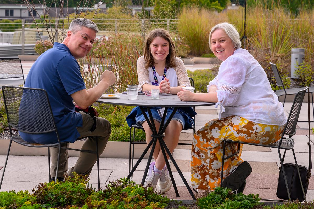 Parents and student sitting at a table outside smiling for the camera
