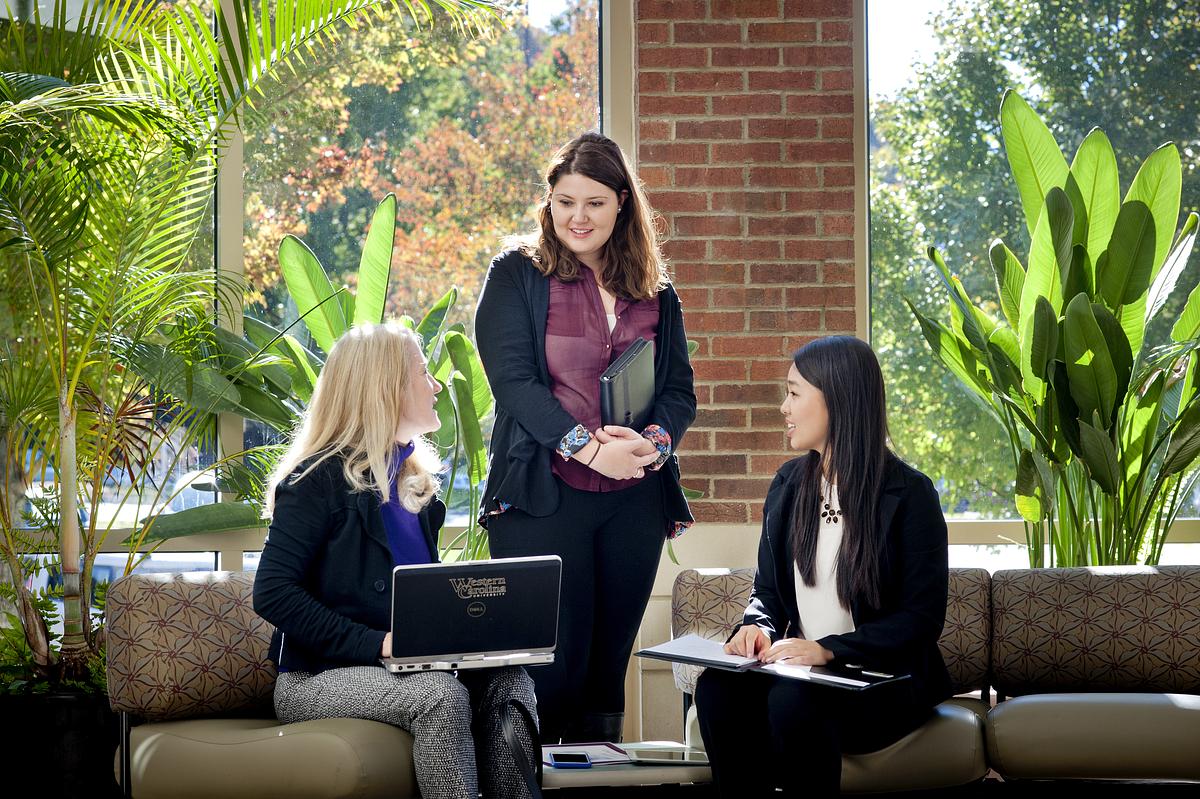 Students and staff gathered around talking over a laptop