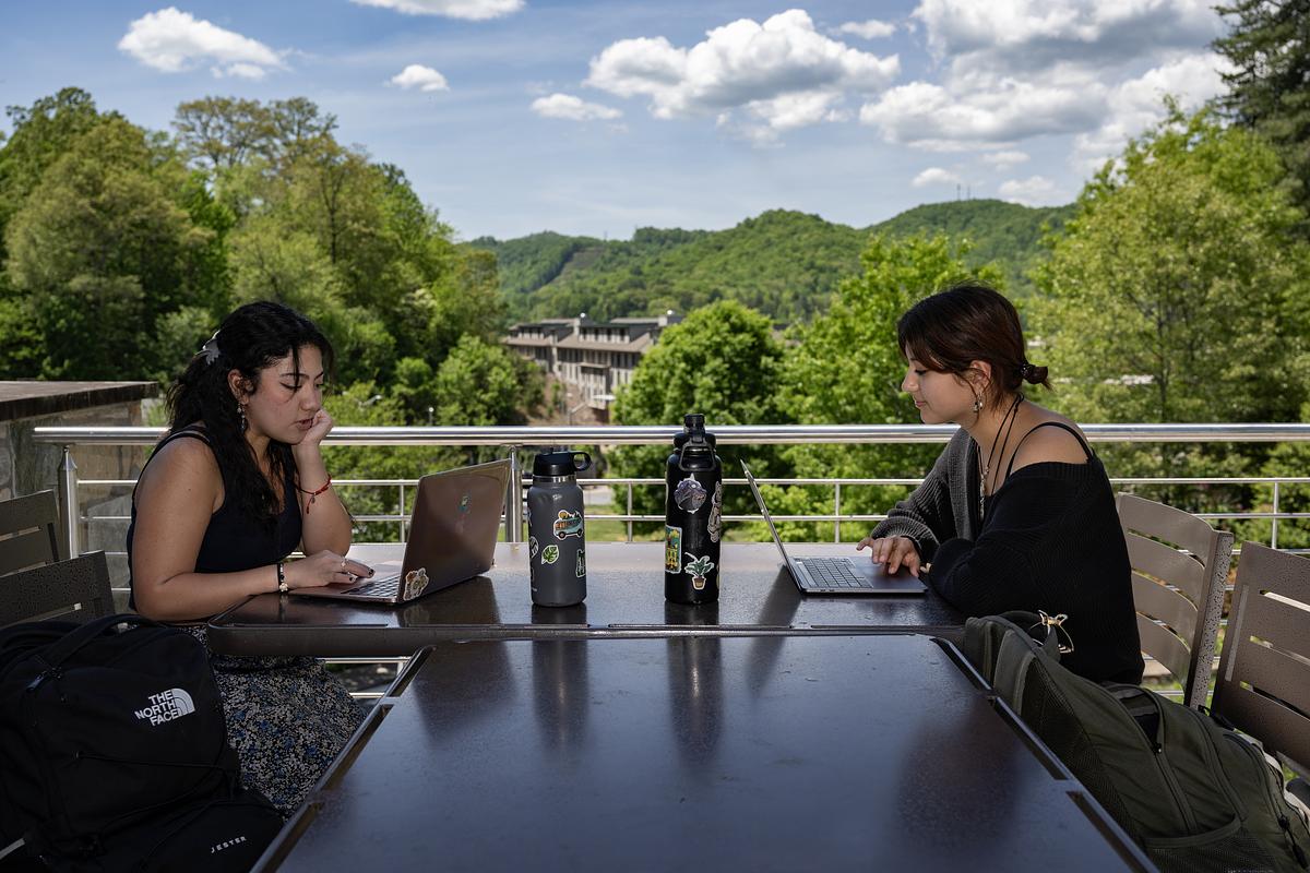Students at a table outside working on their laptops