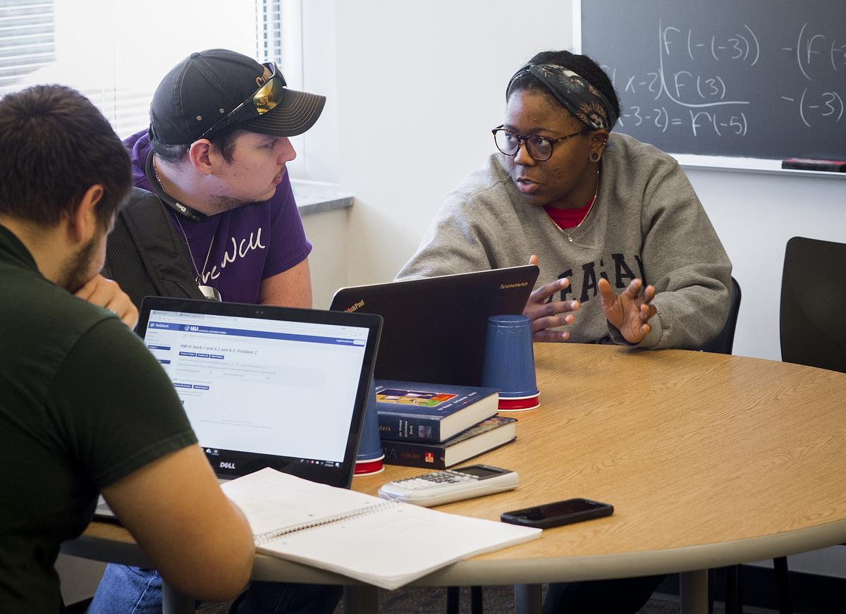 Tutor guides students as they work on their laptops