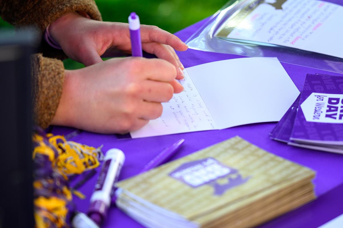 Student filling out a card on a table with scattered WCU merchandise