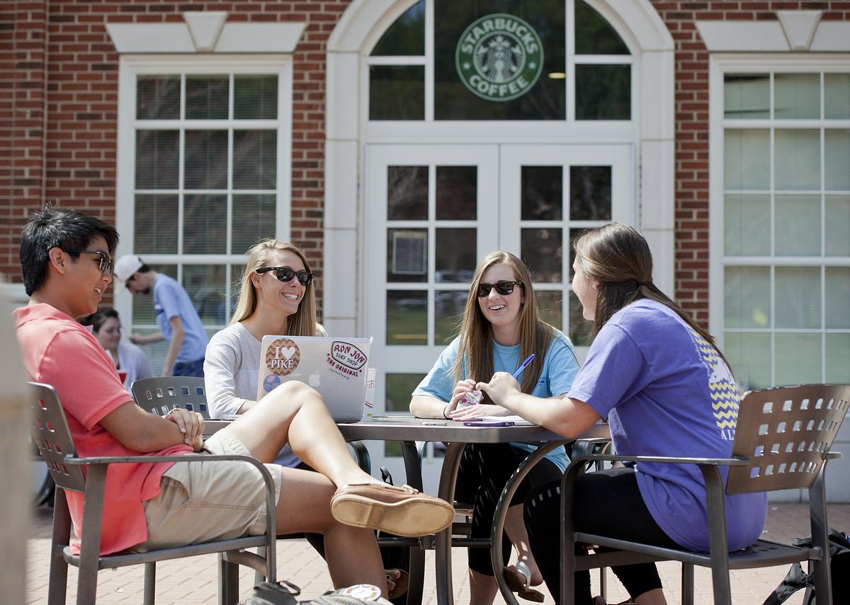 Ðǿմ«Ã½ students drink coffee in front of Starbucks.