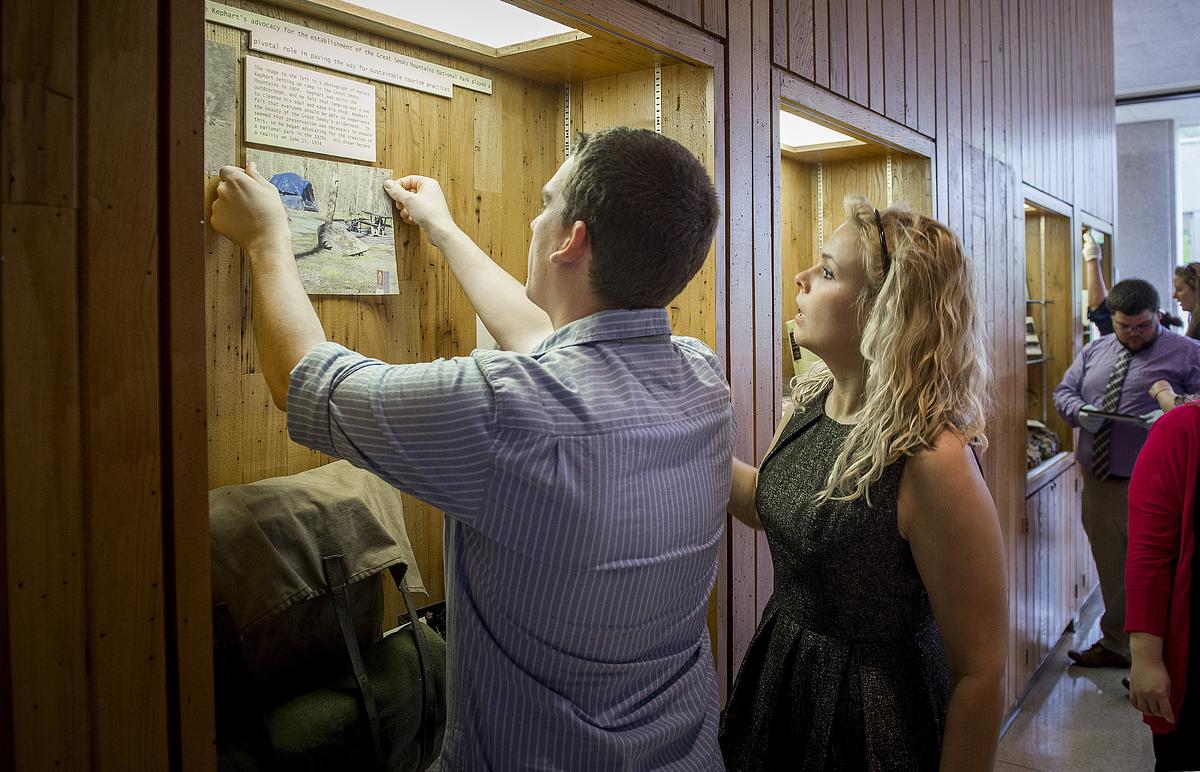 People adjusting an item in a public history display booth