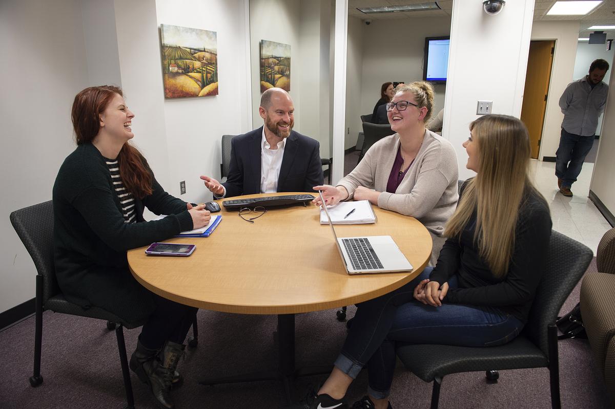 Psychology students and faculty sitting around a table talking 