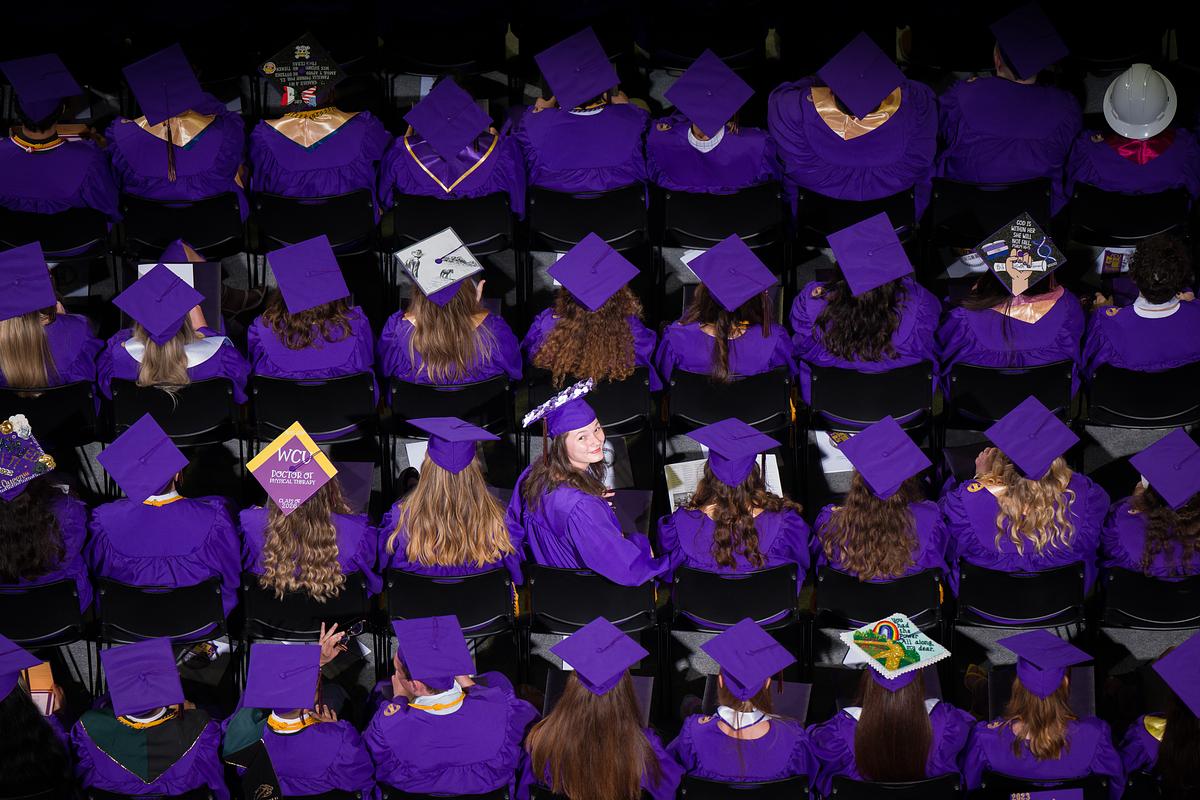 Graduates sitting in rows with the view from above them looking down at their graduation caps