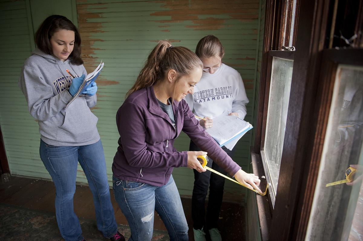 Interior design students taking measurements in a room before work