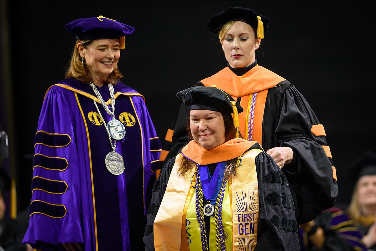Student wearing First Gen stole walking across the stage to get master's degree