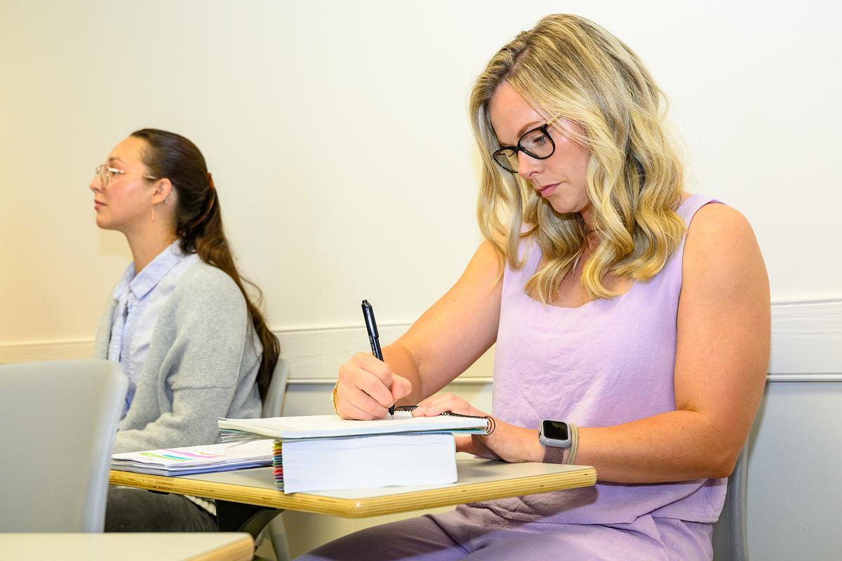 Social work student sitting at a desk and taking notes during a lecture