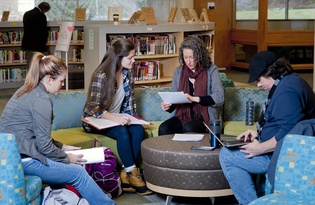 Undergraduate research student and professor in discussion over various documents