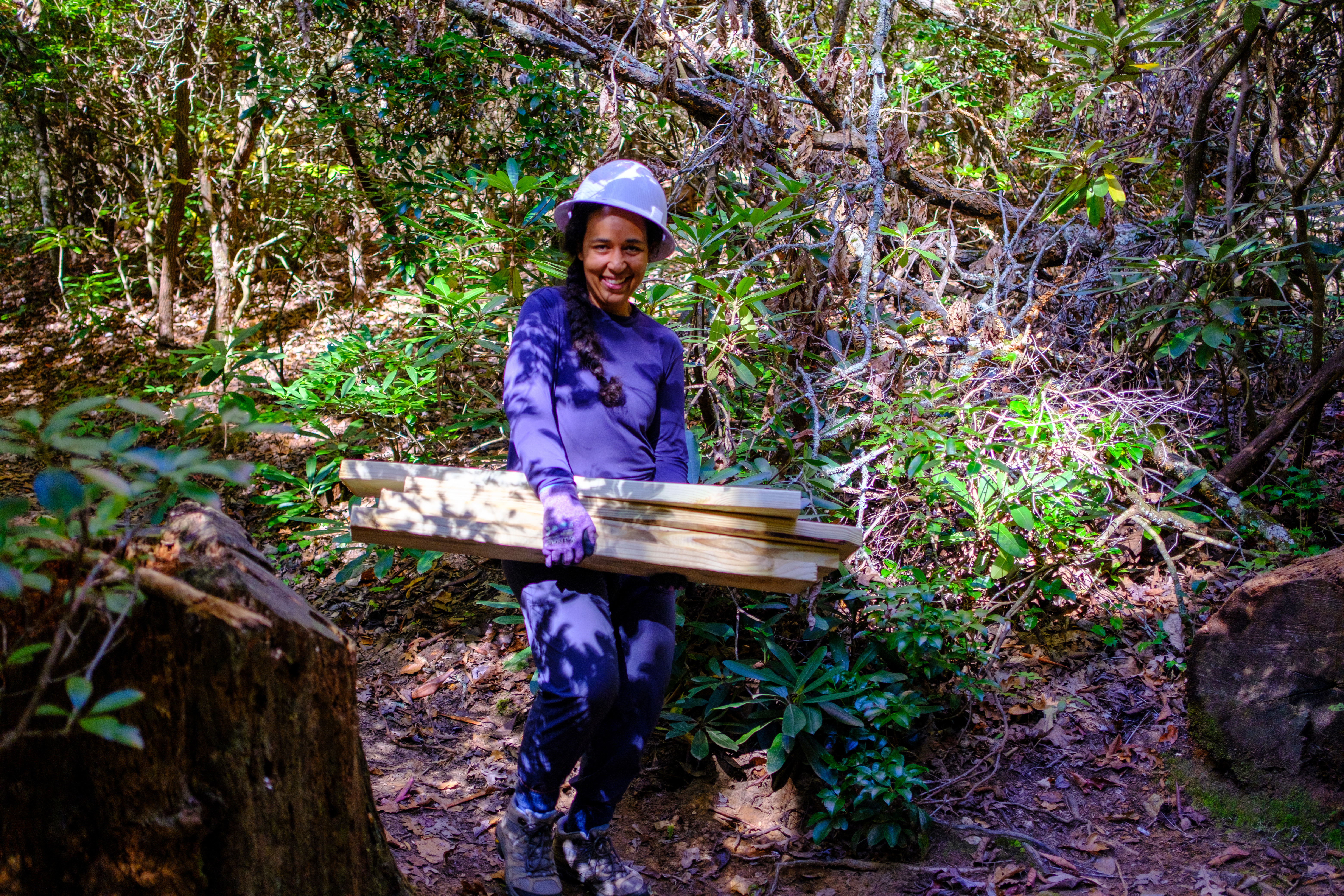 Fern Chagas carries wood to help with trail repairs