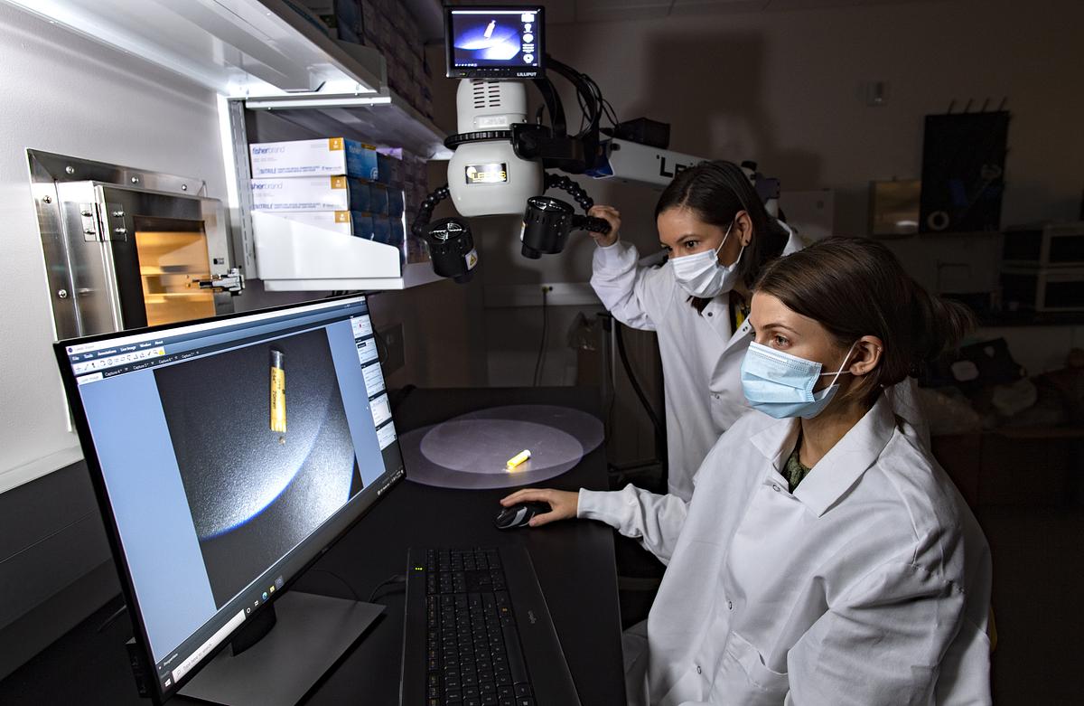 Forensic science students observing material on a monitor connected to a microscope in the lab