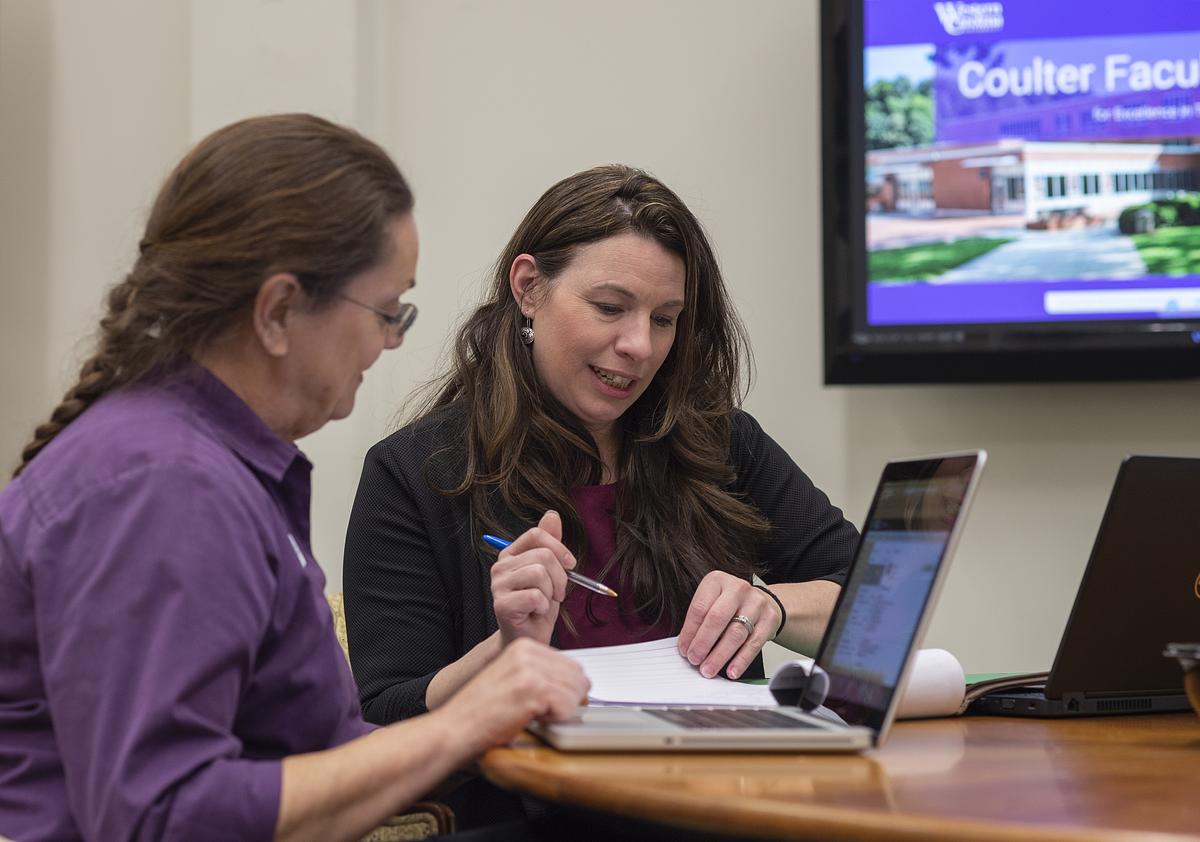 Coulter Faculty Commons staff helping with documents at a table