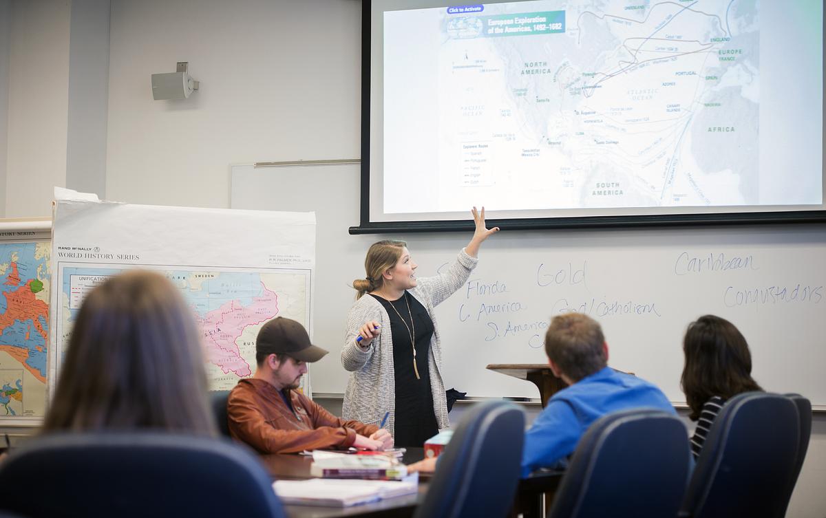 Student pointing at a screen during a presentation in a History Education class