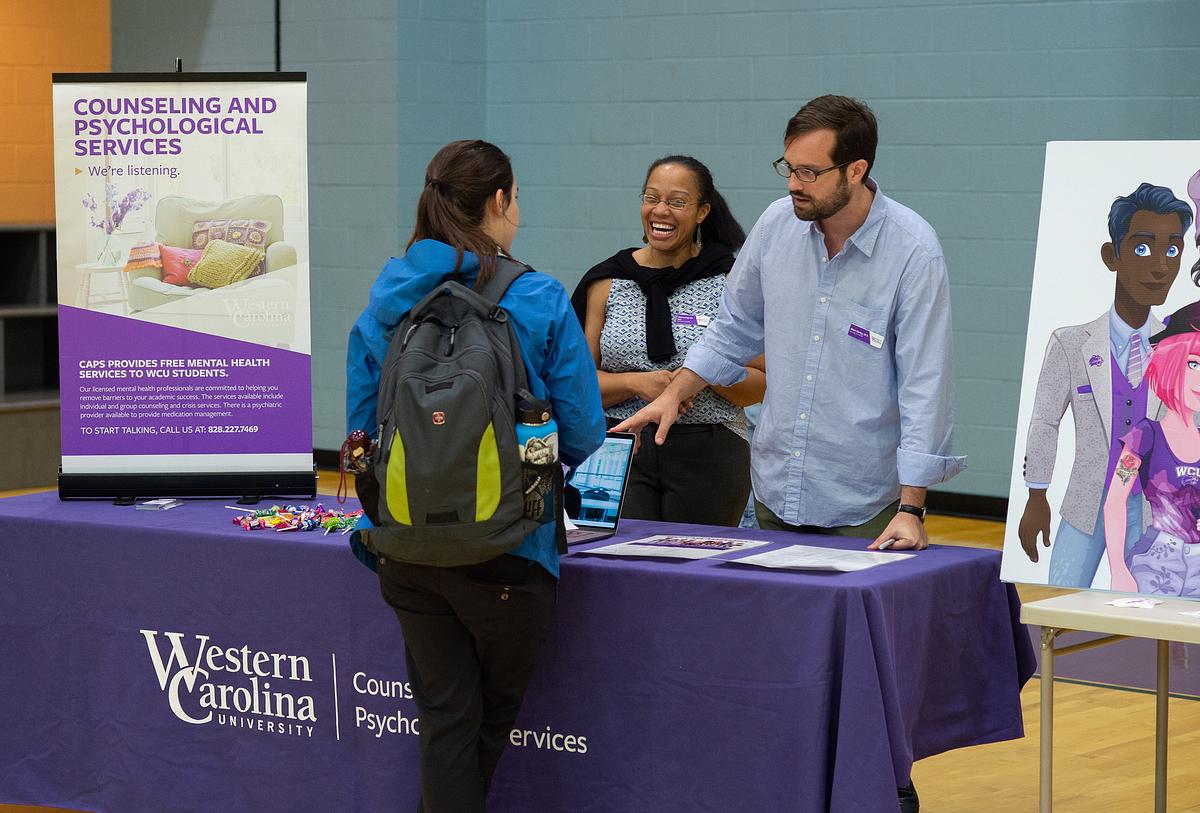 Staff showing a student various pamphlets at a table during the Health and Wellness Fair