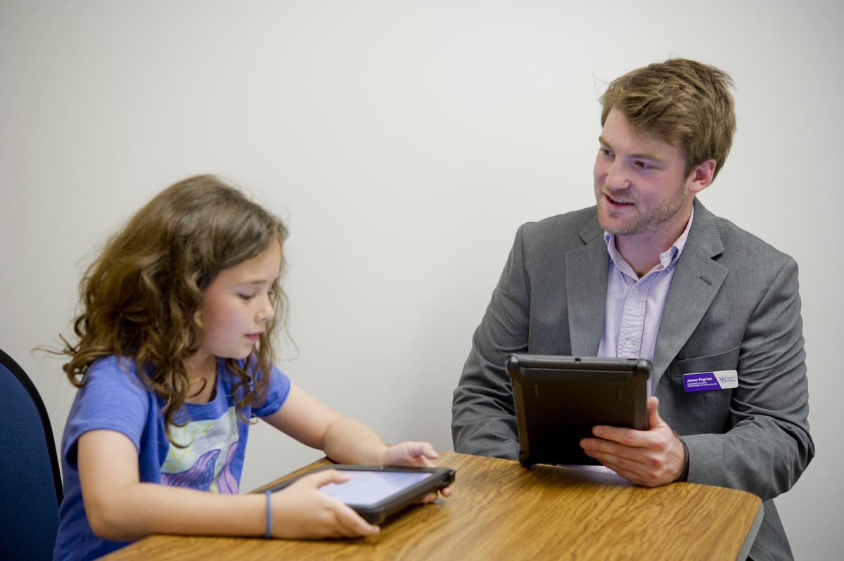Psychology graduate student working with a child at a desk