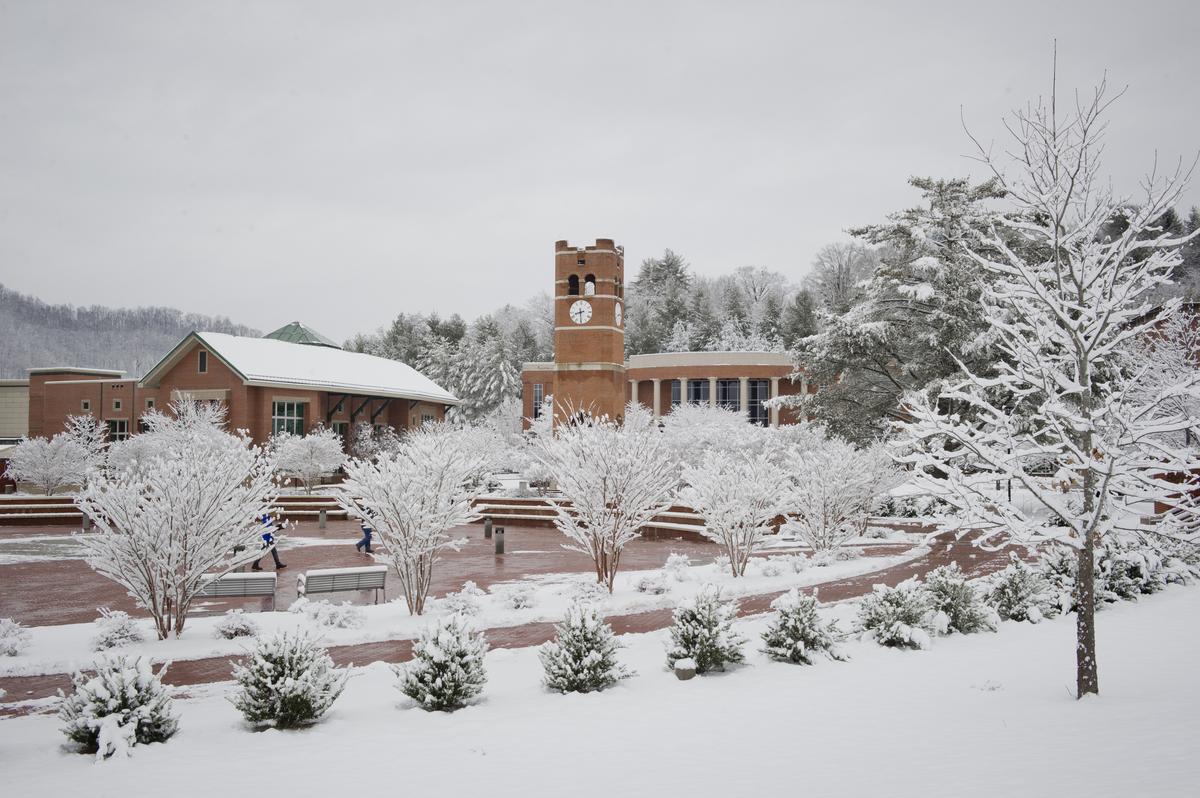Snow falling across campus with the Alumni Tower in the background