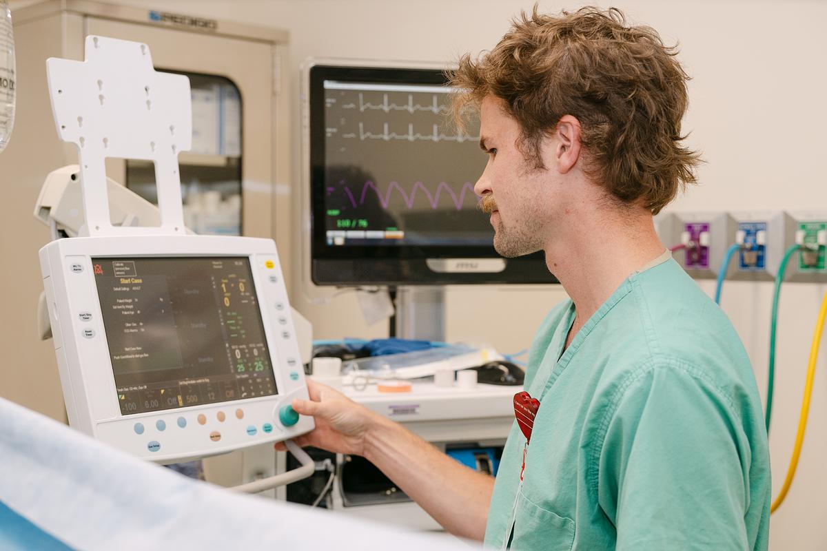 Nurse reading a medical monitor by a hospital bed