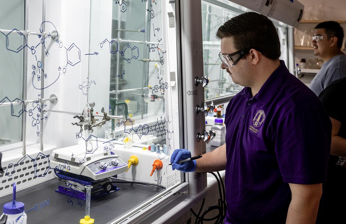 Students working in the lab drawing out molecular equations on glass