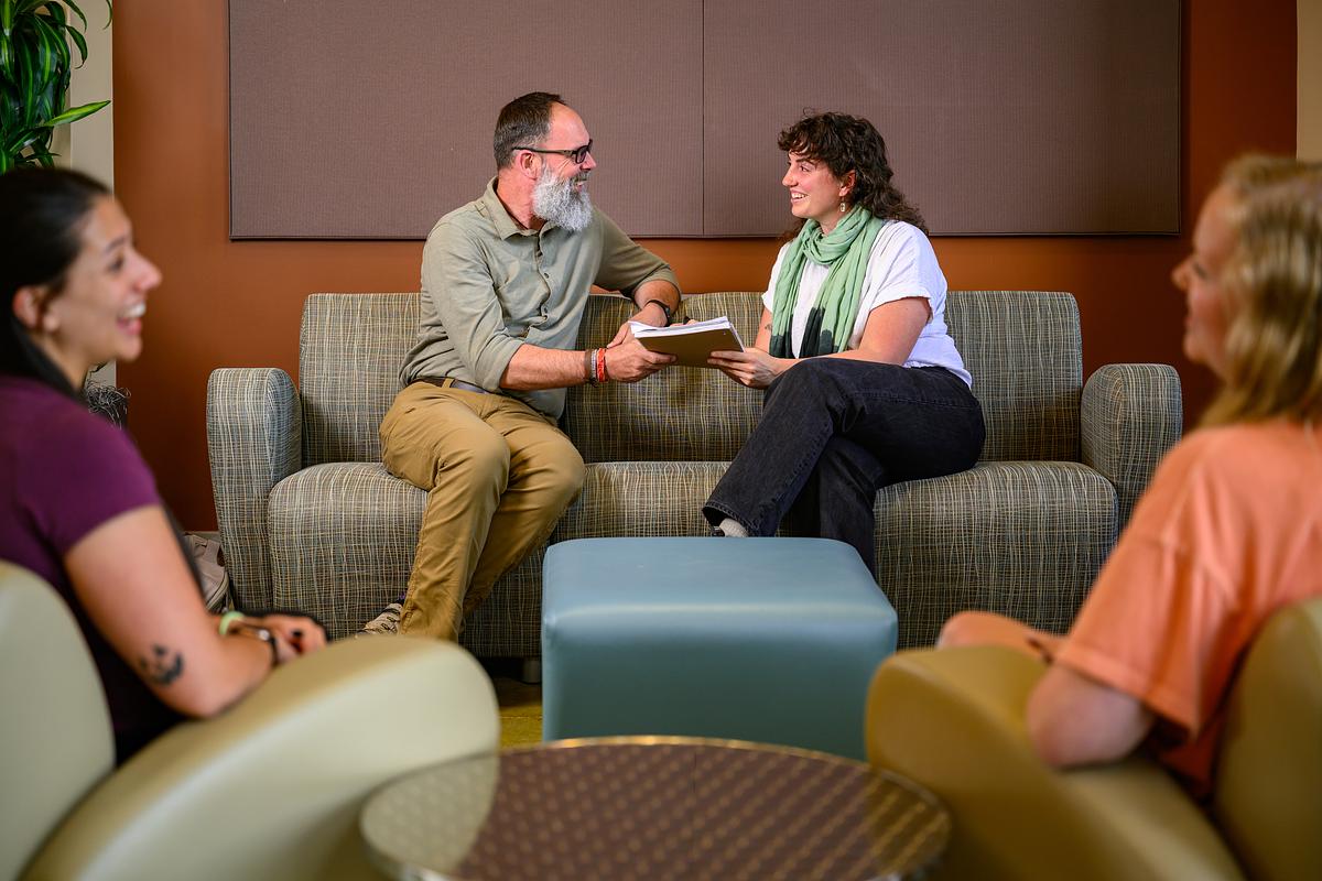 Two people meet and chat on a couch with two people chatting in the foreground