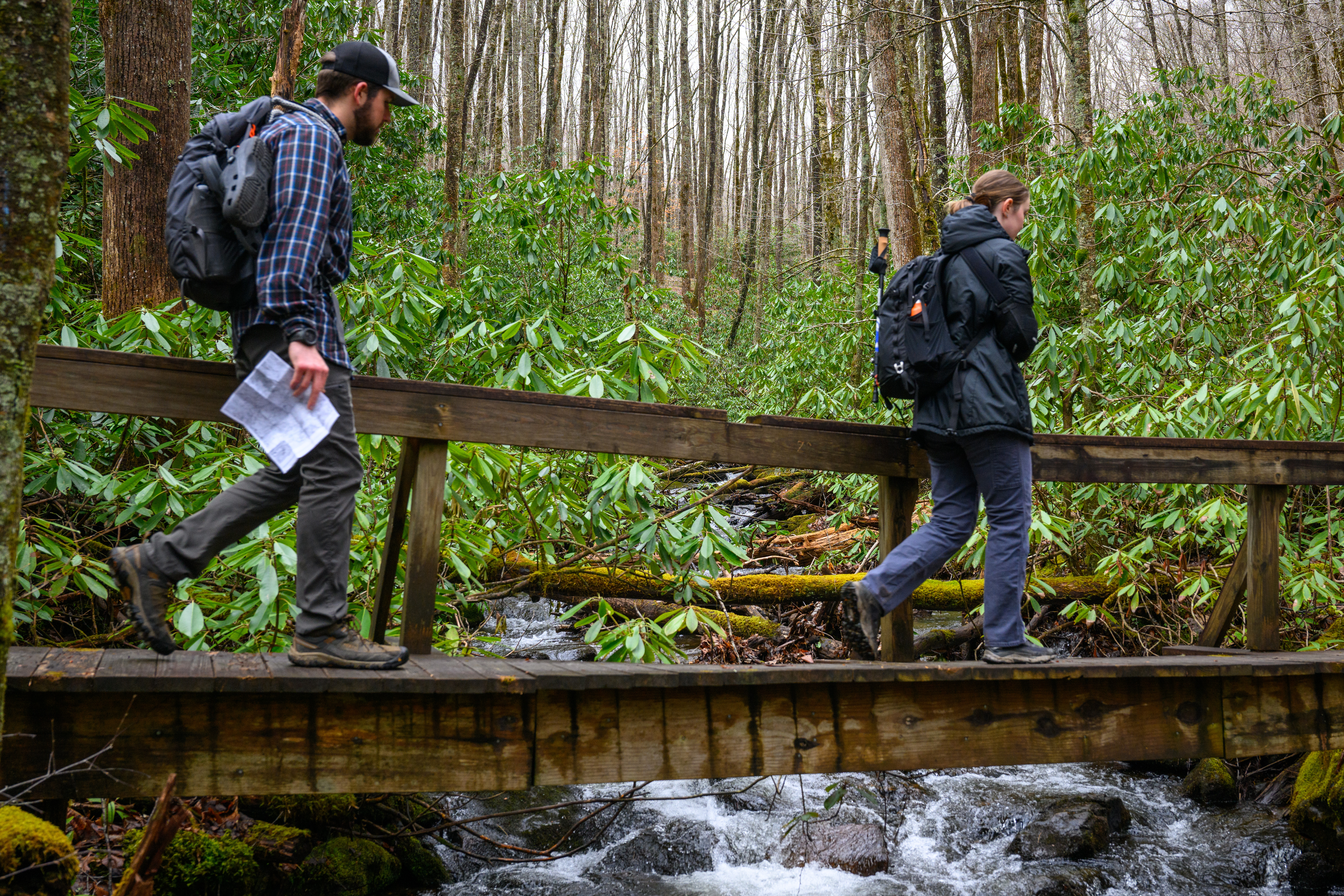 Two students crossing a bridge over a creek