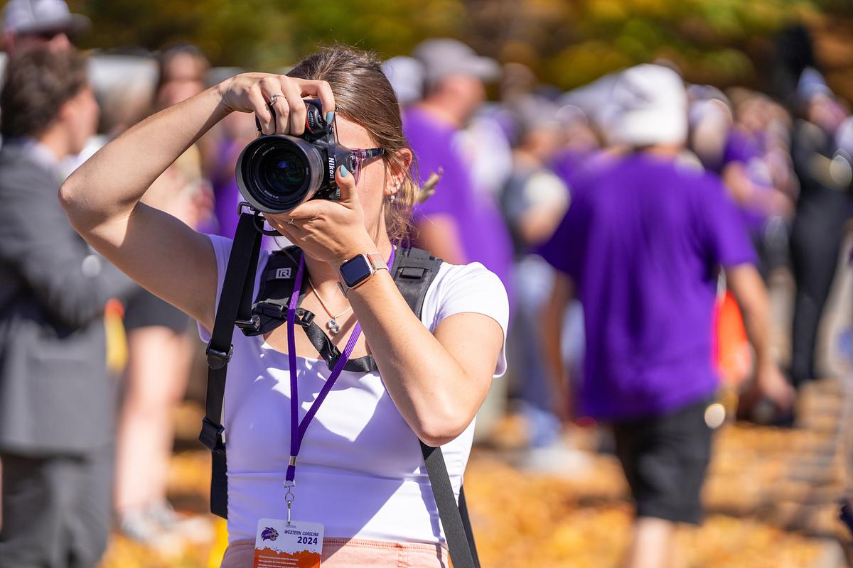 Priya showing students how to take a video with an updated video recorder