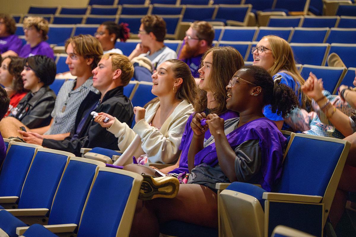 Students in class listen to a lecture and take notes while sitting in an auditorium