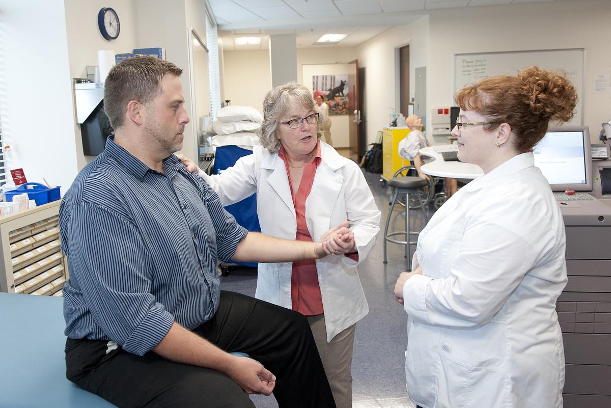 Professor and student practice on a patient for a medical demonstration