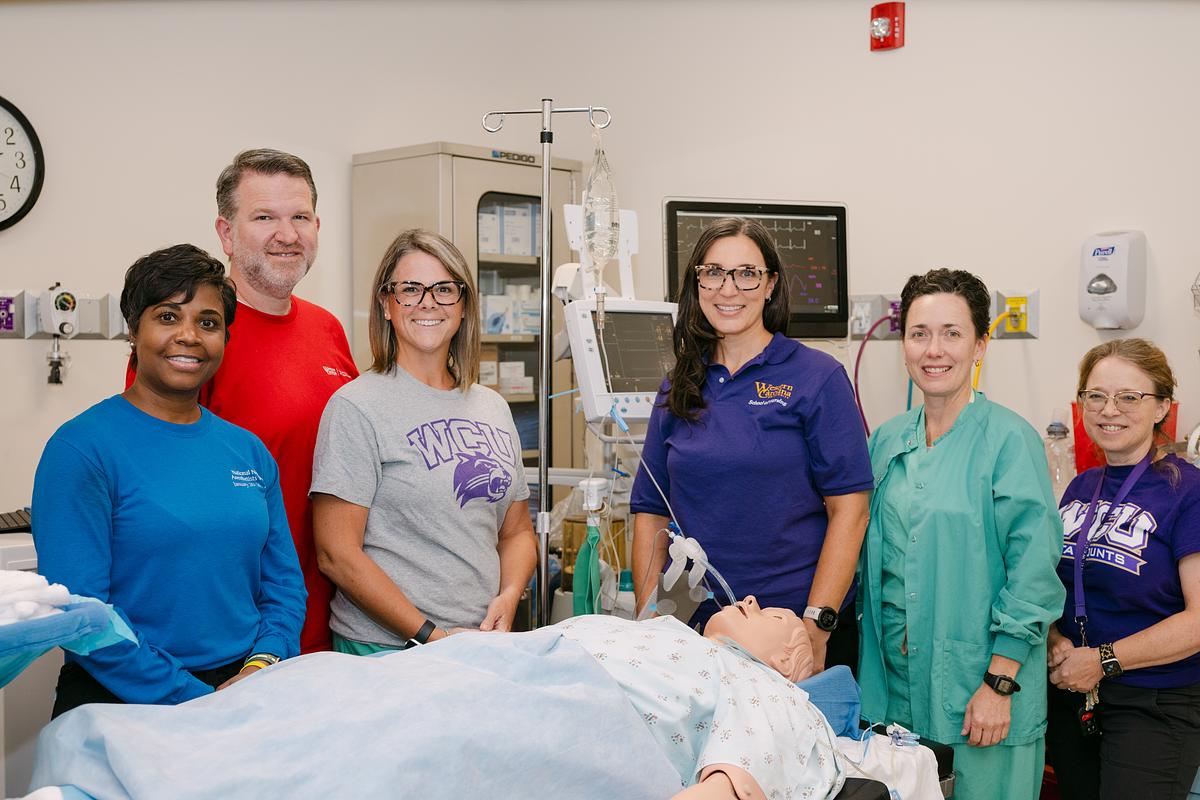 Faculty of the nursing simulation lab stand together smiling for a group photo