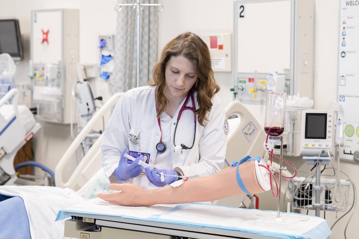 Nursing student works on a hand model for practice in the lab