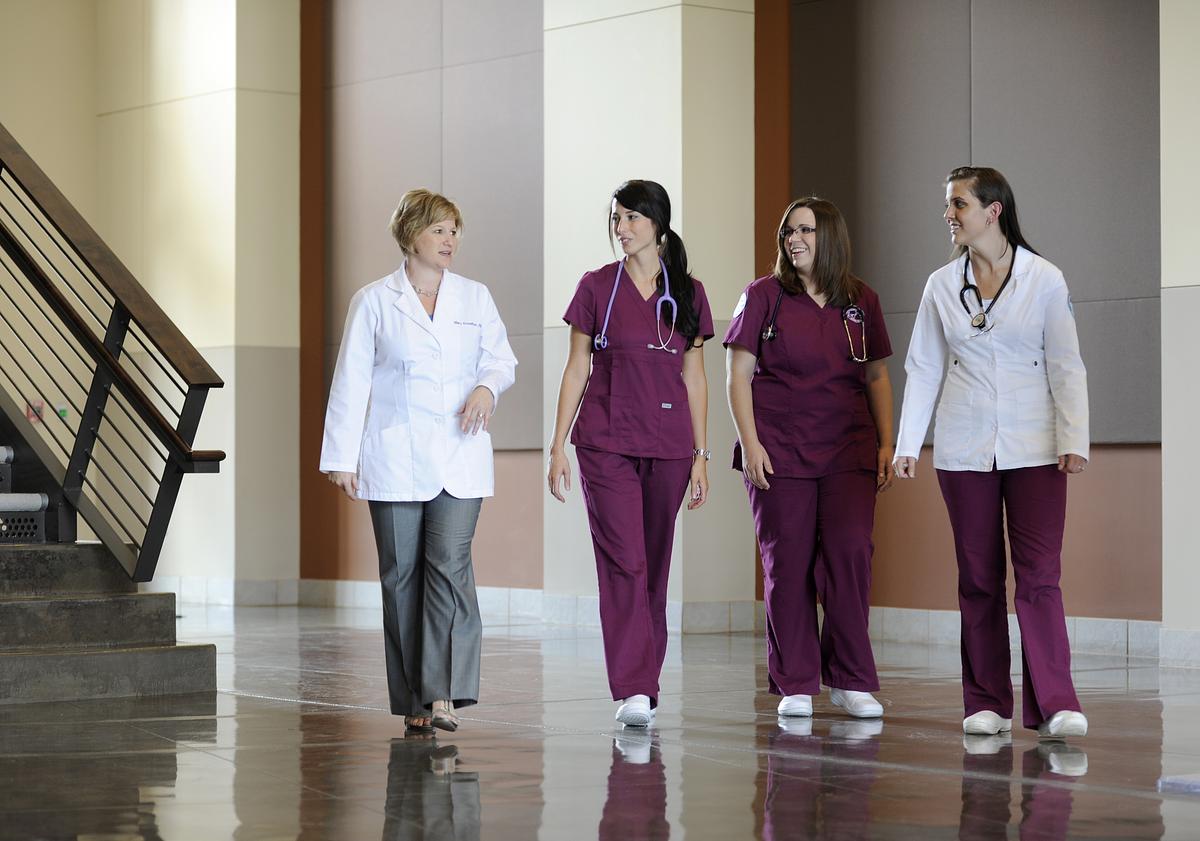 Nurse practitioners and doctors talking together as they walk down a hall together