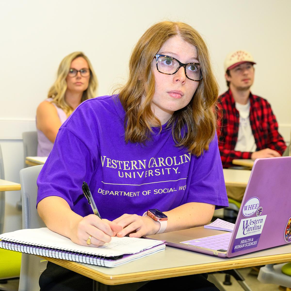 Social sciences student sitting at their desk taking notes during class