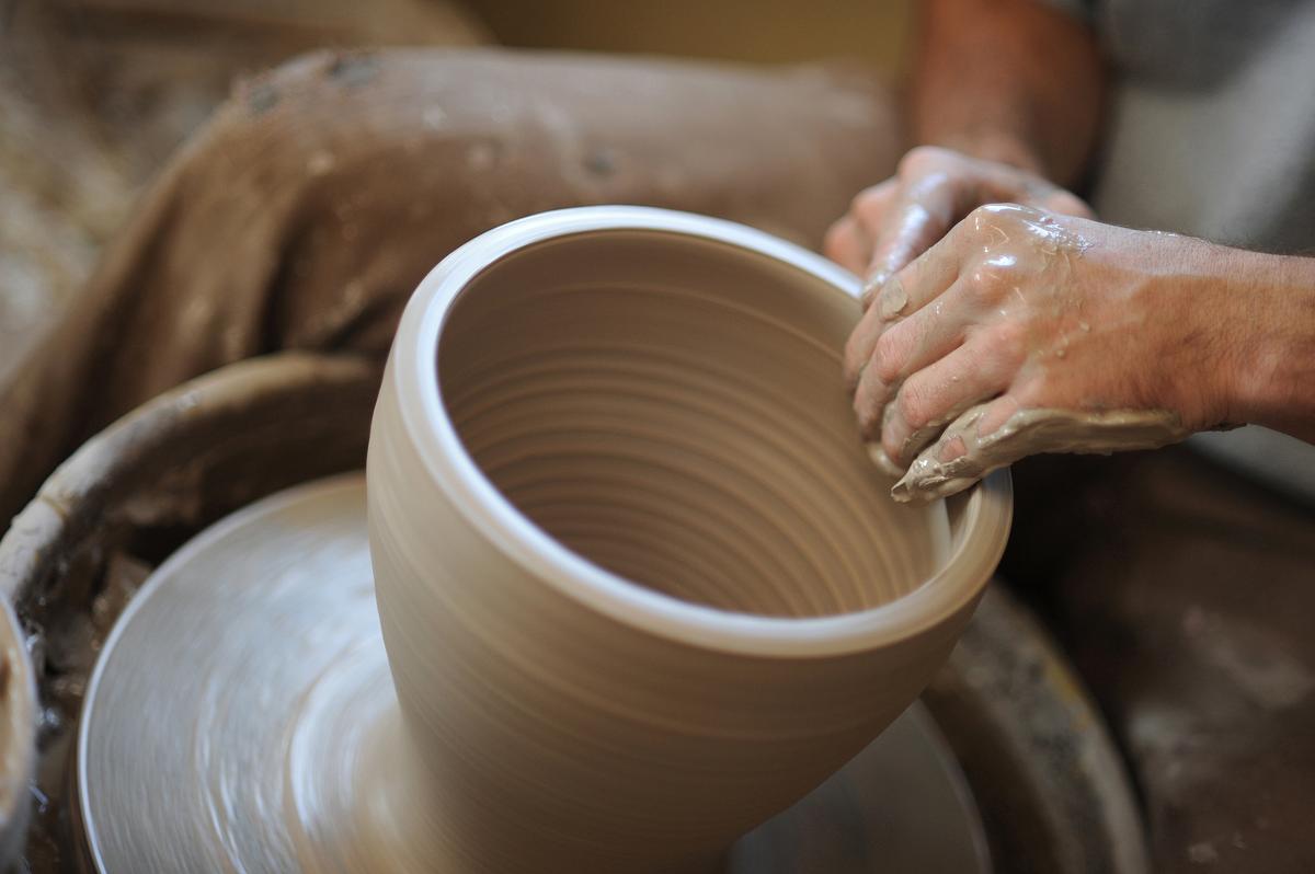 Student using a pottery wheel making a vase