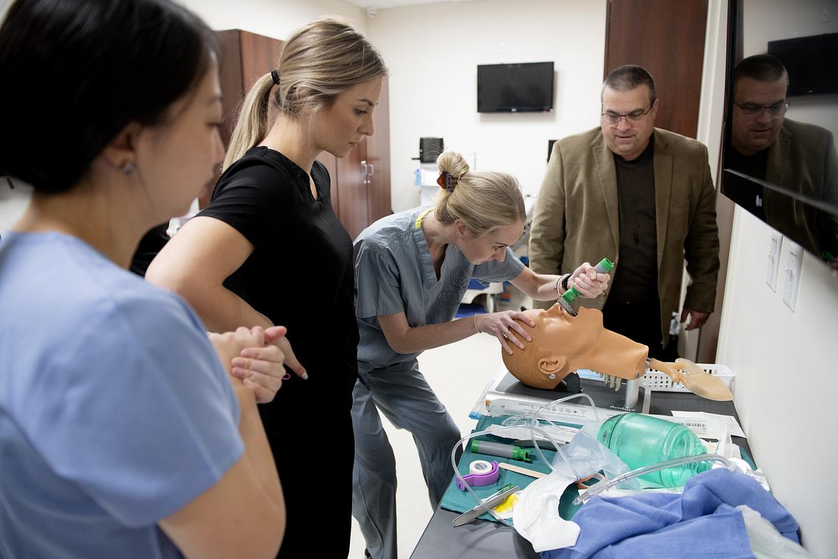 Teacher and students working on a manikin for a medical procedure tutorial