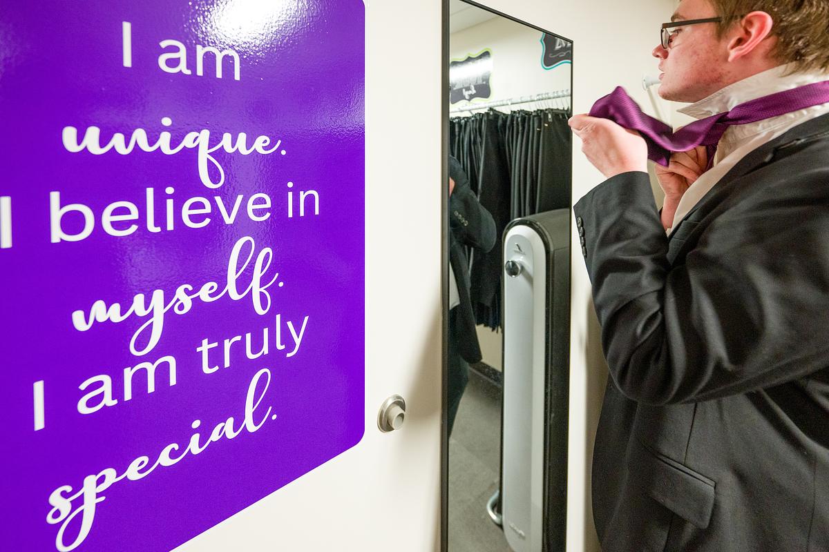 Image of a person tying a tie in front of a mirror