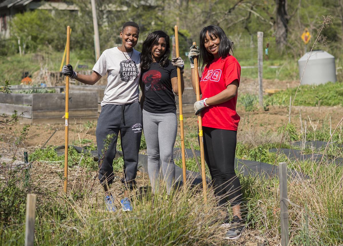 Students together hugging for a photo as they work in the Community Gardens
