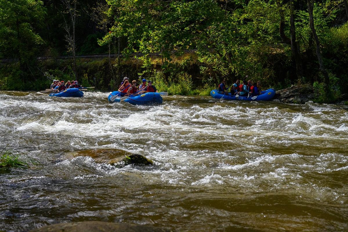 Three rafts with students and guides travel down a section of the Nantahala River 