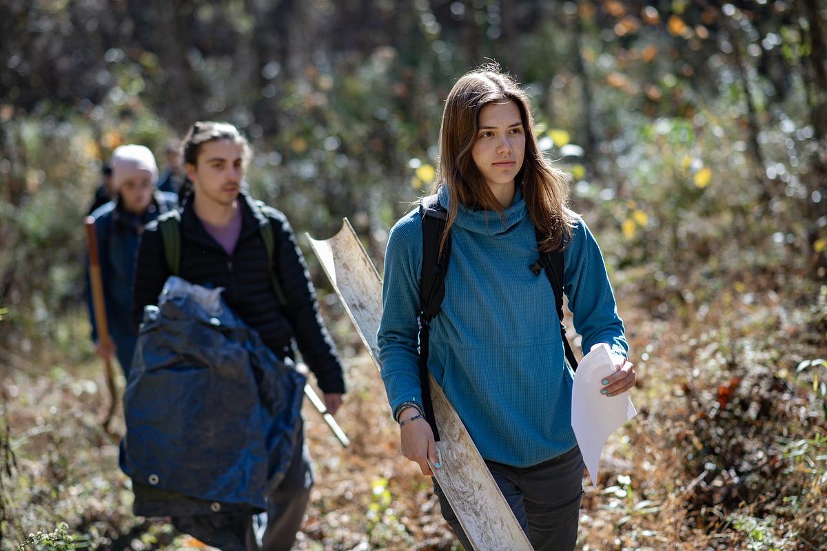 Students hiking in the woods with hydrology research gear