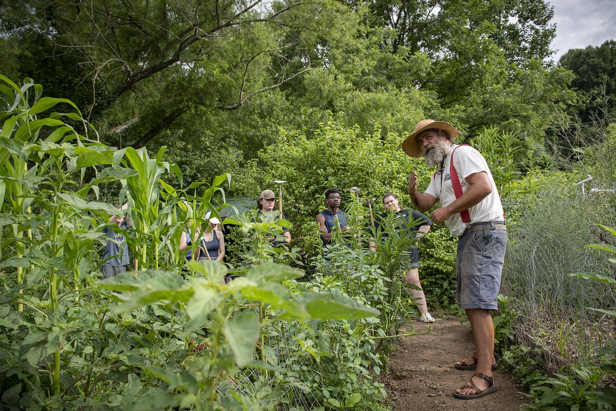 Farmer showing students how to work in a garden