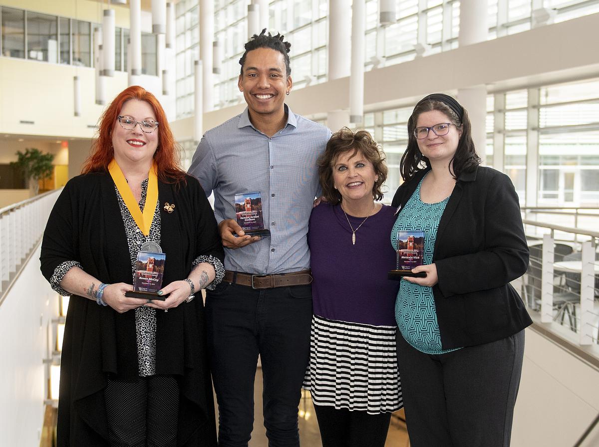 Students and faculty stand for a group photo holding up their trophies
