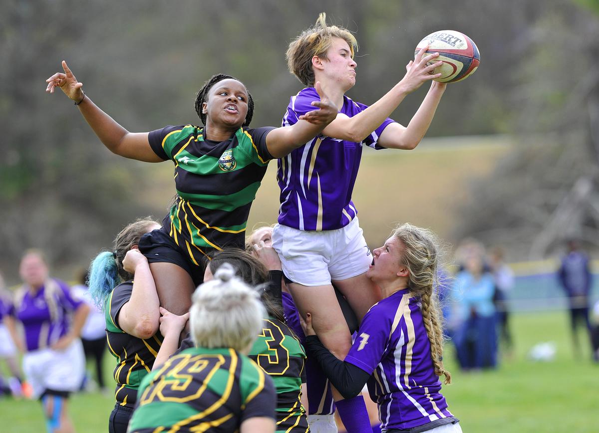 Women's rugby match with a catamount player catching the ball in the middle of a clash of teams