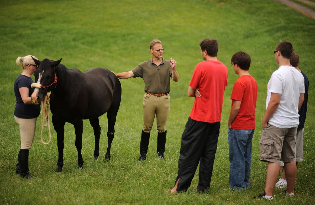 Professor David Dorondo speaking to students in a field with a horse and its trainer