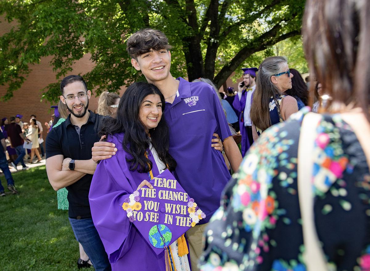 Group of students wearing purple school shirts at outdoor campus event with green trees and lawn
